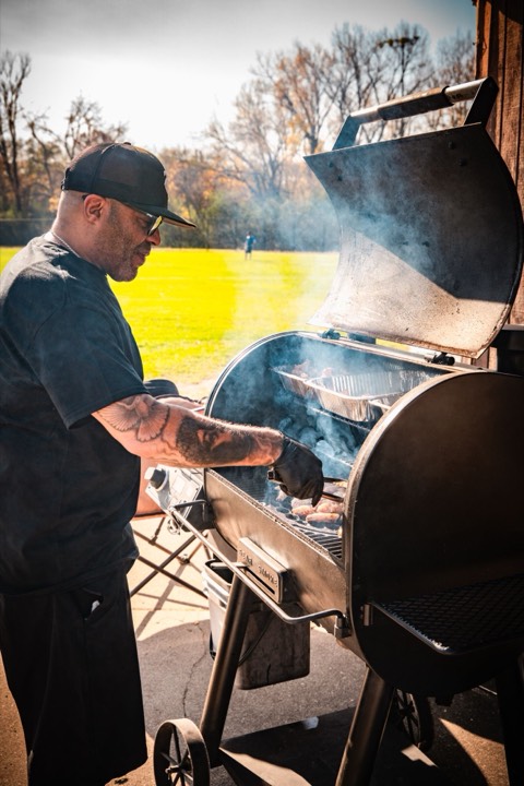 Uncle B turning chicken in a smoking pellet smoker